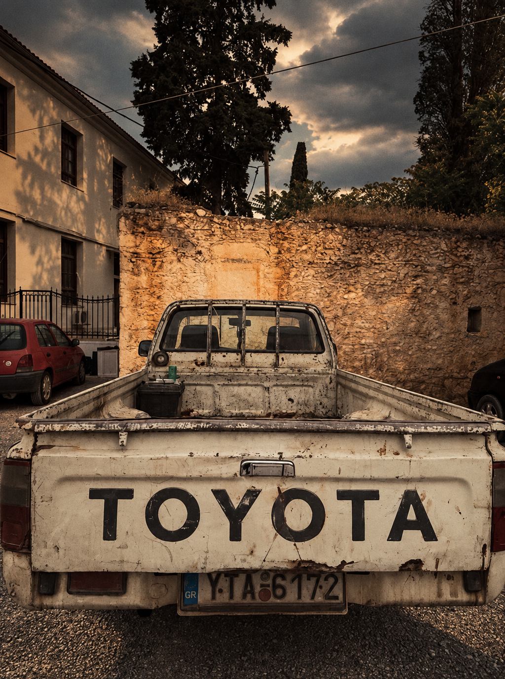 Weathered white Toyota pickup against a rustic stone wall